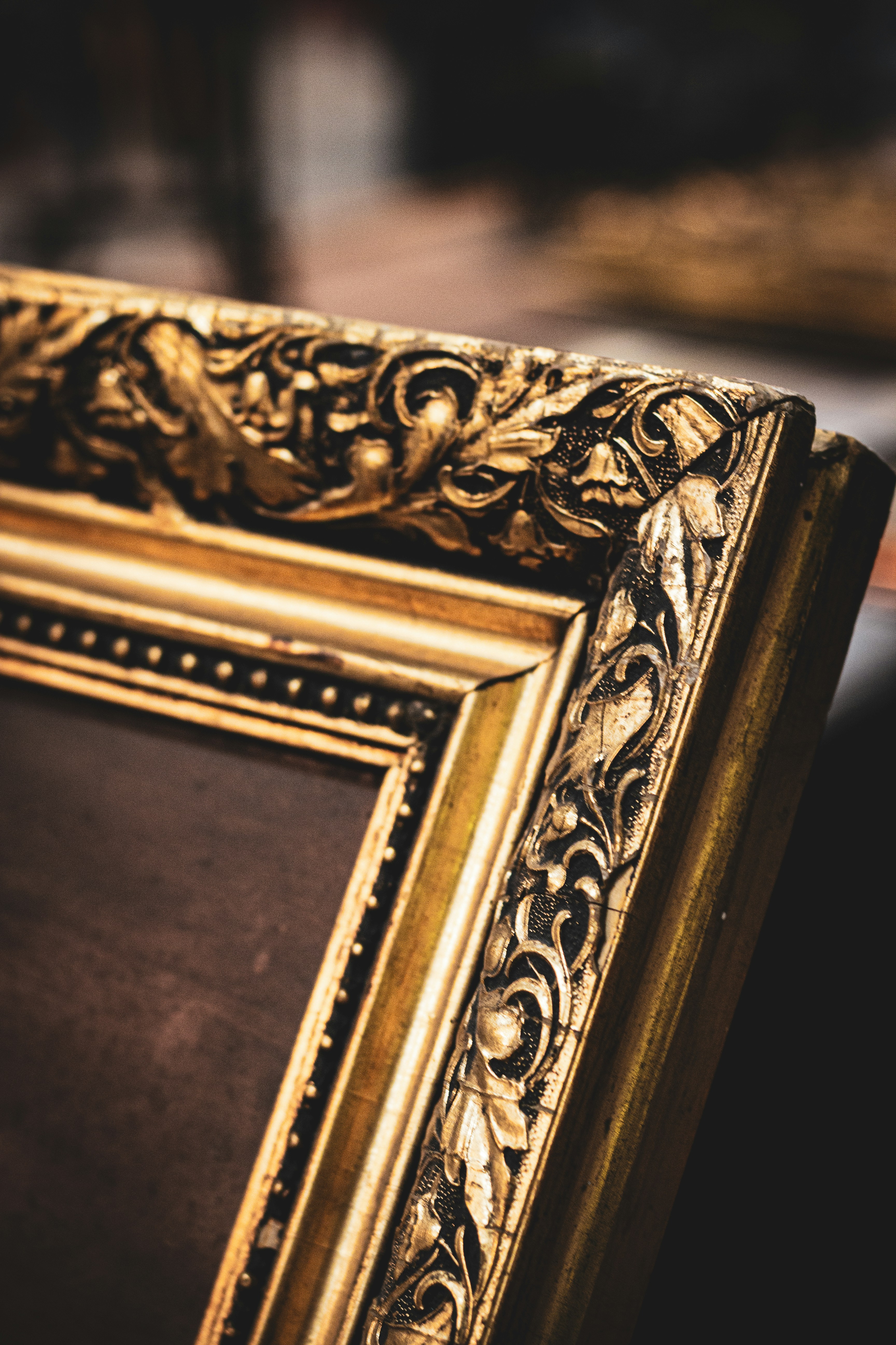 Close-up of an ornate gilded antique picture frame corner with carved floral and scroll detailing